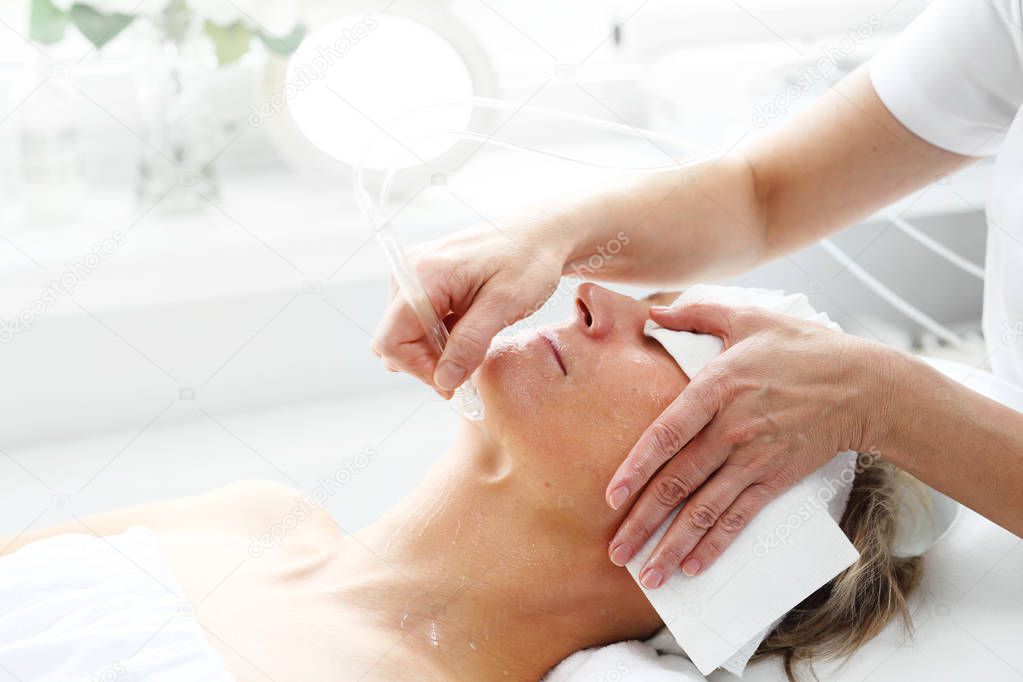 Oxygen oxybrasion. The beautician performs oxygen oxybrasion treatment on the skin of a woman's face. Care treatment, skin cleansing