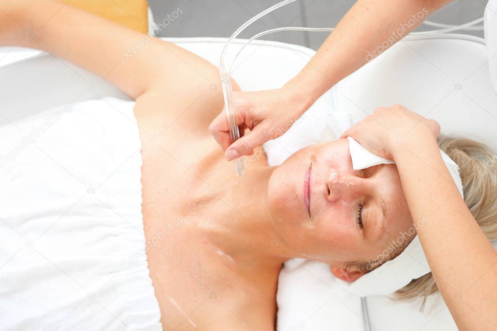 Oxygen oxybrasion. Smooth neck and cleavage. The beautician performs oxygen oxybrasion treatment on the skin of the neckline and neck of a woman. Care treatment, skin cleansing