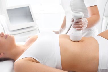 Göbek kaldırma. Karın derisine masaj yapılan kozmetik kliniğinde bir kadın..