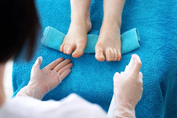 美容室でペディキュア 抗菌剤による足の消毒美容師は女性の足にペディキュア治療を行います 青の構図 手を触れずに本物の絵 — ストック写真