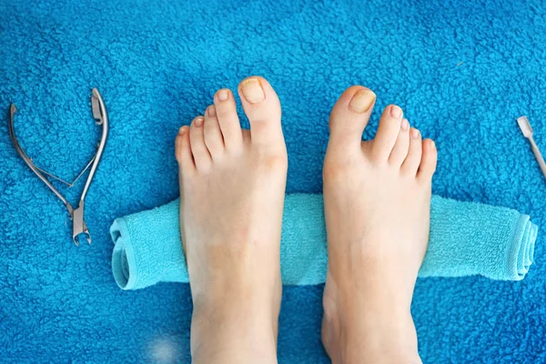 Pedicure, bare feet. Female feet without retouching. Female feet on a blue background. Natural photo without retouching