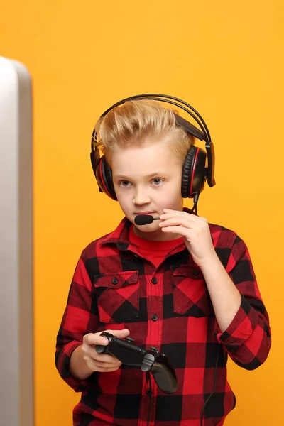 控制台游戏 小男孩用耳机玩电脑游戏 年轻英俊的白人男孩穿着黄色背景的红色衬衫 水平的 笔直的 — 图库照片