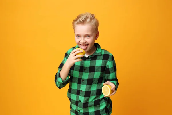 Boy is eating a lemon, funny faces of a child.Expression and joy of the child. The boy eats a lemon, the child\'s funny faces.Happy child, facial expressions, energy and fun.