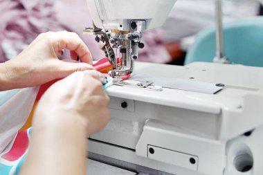 Bir makineye dikiş dikmek. Çalışan kadın dikiş odasına dikiş dikiyor. Terzi kapağı dikmiş olmalı. Bir kadın giyim fabrikasında çalışıyor..