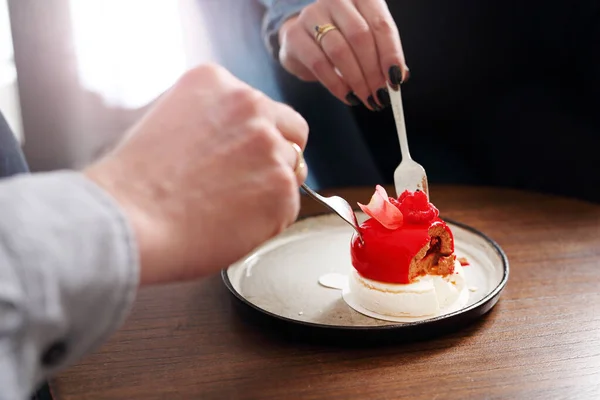 Red chocolate heart, sweet dessert. A woman and a man are eating sweet dessert hearts.