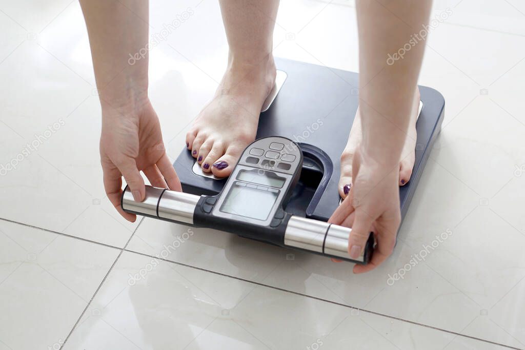 Weighing and measuring body composition. Woman on analytical balance.Analytical balance, body composition measurement with a professional scale.