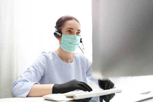 Remote work. A woman in a surgical mask works on the computer. Work during the plague