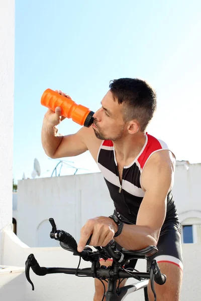 Spinning, Circuit training on a stationary bike. Hydration during training. the athlete drinks an isotonic drink while riding a bicycle.