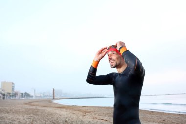 Okyanusta yüzme eğitimi. Termal köpüklü adam denizde su sporları yapıyor..