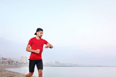 Plaj eğitimi. Plaj koşucusu. Genç atletik çekici bir adam deniz kenarında tek başına koşuyor..