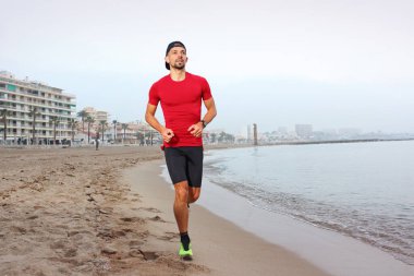 Kumsalda koşmak. Genç atletik çekici bir adam deniz kenarında tek başına koşuyor..