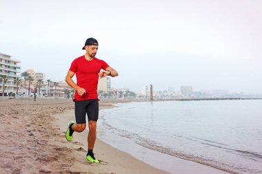 Açık hava eğitimi. Kumsalda koş. Genç atletik çekici bir adam deniz kenarında tek başına koşuyor..