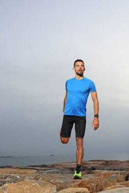 Eğitimden önce ısınma. Spor kıyafetli bir adam esneme egzersizleri yapıyor..