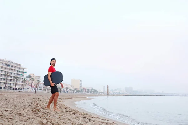 Skimboard, man swims on the board. A man in thermal foam does water sports in the sea.
