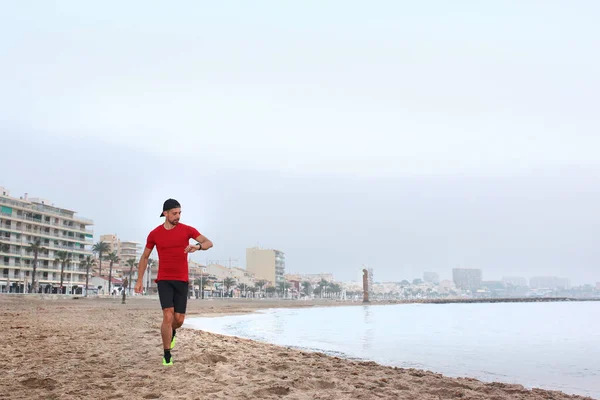 Outdoor training. Run on the beach. A young athletic attractive man runs alone by the sea.