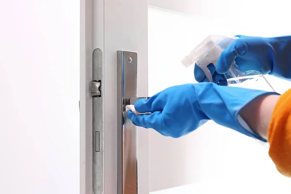 Cleaning the house, cleaning door handles. Prevention and prevention of infection. The woman cleans the apartment.