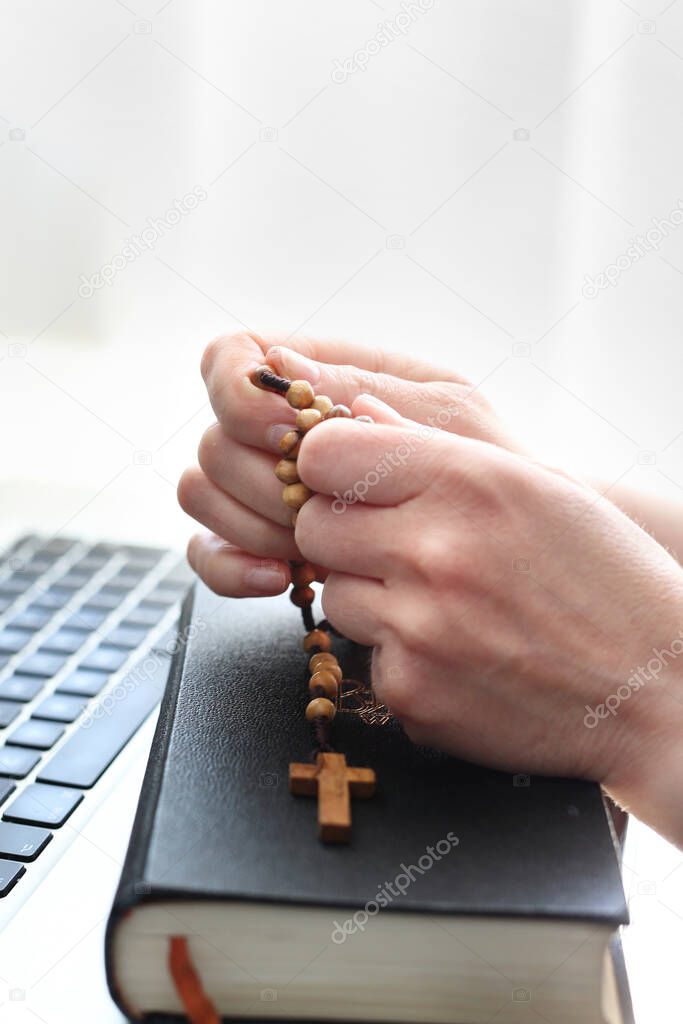 Faith and prayer. A woman prays at the rosary. A woman prays on a rosary in front of a computer.