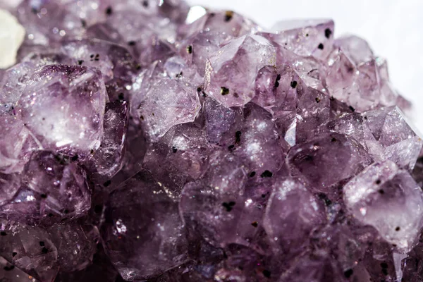 Gemstone Amethyst closeup as a part of cluster geode filled with rock Quartz crystals.