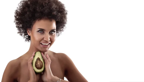 African american woman with afro hairstyle holding avocado — Stock Photo, Image