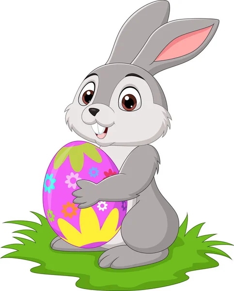 草の中にイースターエッグを保持する漫画の小さなウサギのベクトルイラスト — ストックベクタ