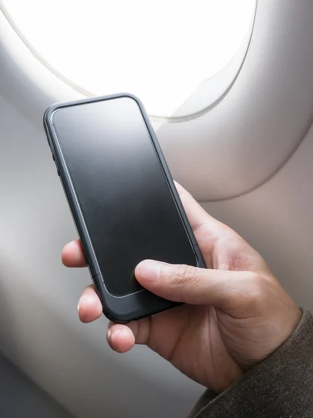 Hand holding cell phone on airplane — Stock Photo, Image