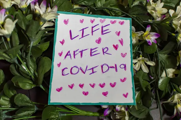 心と様々な色の花とCovid 19コロナウイルスメッセージの後の生活 — ストック写真
