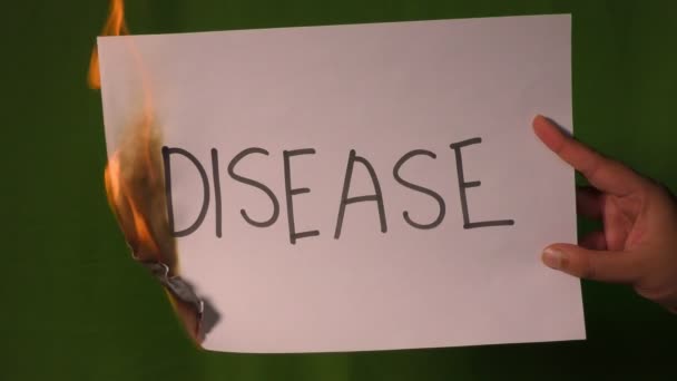 Een Hand Houdt Het Brandende Papier Met Tekst Van Ziekte — Stockvideo