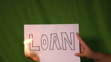 Bir el, üzerinde kredi metni olan yanan kağıdı yeşil ekranda tutuyor..