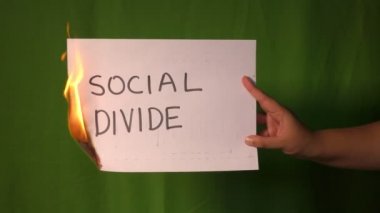 Bir el, sosyal bölme sözcüğünün bulunduğu yanan kağıdı yeşil ekranda tutar..