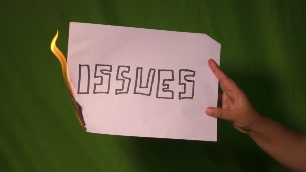 一只手拿着燃烧的纸 上面有问题文字 放在绿色的屏幕后面 — 图库视频影像