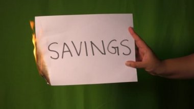 Bir el, üzerinde tasarruf metni olan kağıdı yeşil ekranın arkasında tutuyor..
