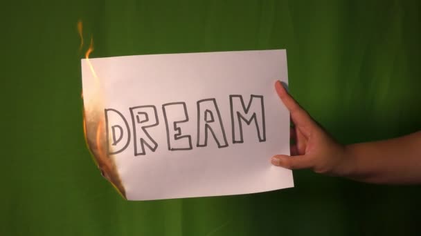 手の後ろの緑の画面に夢のテキストの単語と燃える紙を保持します — ストック動画