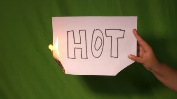 一只手把火热的纸放在绿色的屏幕后面 上面写着热的文字 — 图库视频影像