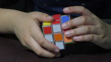 Rubik küpü dönen bloklarla çözmeye çalışan bir kız