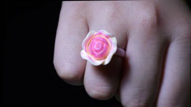 Bir kadının parmağında pembe renkli gül desenli bir yüzük.