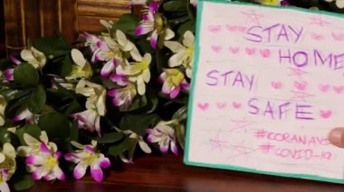 Evde kal. Coronavirus covid-19 posteri sırasında güvende ol. Masanın üzerinde çok renkli çiçekler olsun..