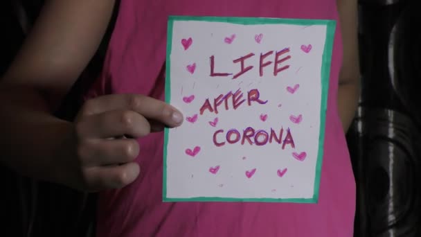 コロナウイルスの後の生活暗闇の中で女の子の手の中にCovid 19グリーティングカード — ストック動画
