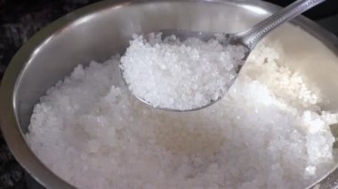 Bir el kaşıkta ve kabın içinde şekeri gösteriyor ve sergiliyor..