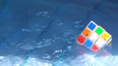 Bir rubik küp mavi suda ve dalgalarda yüzüyor..