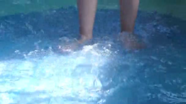 プールの青い色の水の上を歩き水で遊んでいる女の子 — ストック動画