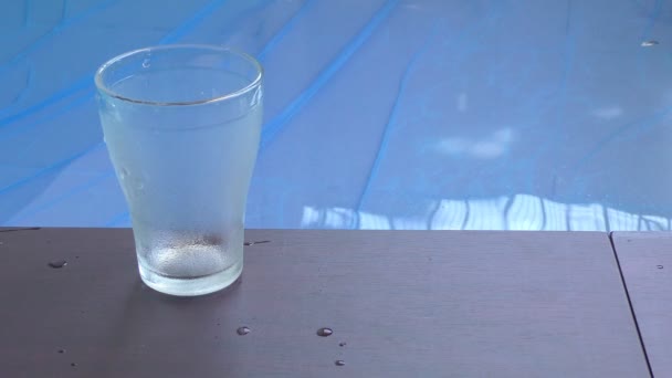 Une main met deux verres sur les côtés de la piscine et les lunettes sont transparentes .
