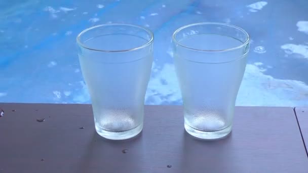 Twee Lege Glazen Aan Zijkanten Van Het Zwembad Van Blauw — Stockvideo