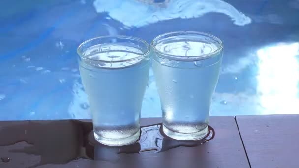 蓝色水波池边的两个玻璃杯和波涛 — 图库视频影像