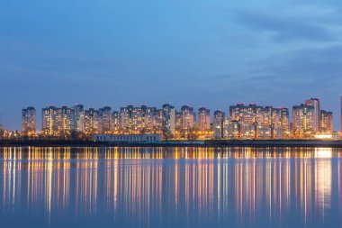 Metropolün gece ışıkları nehrin su yüzeyine yansıyor.
