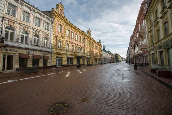 Nizhny Novgorod 'daki Bolshaya Pokrovskaya caddesinde kar yağışı sırasında yankılanan binaların yansımaları bahar güneşinde parke taşlarına yansıyan insanlar olmadan.