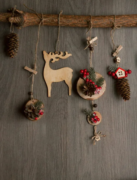 New Year\'s decor. Wooden holiday toys on a dark background. Top view. (Deer, cones, log houses, berries, branches)