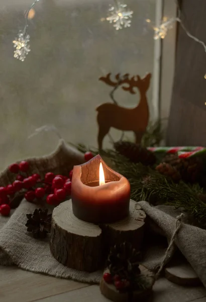 圣诞装饰 红色浆果 窗台上的木制烛台上 立着一支黑色的燃烧着的蜡烛 — 图库照片