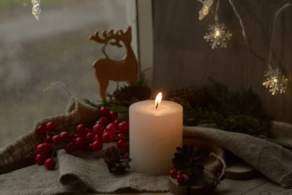 圣诞装饰窗台上的木制烛台上 燃着一支白色的蜡烛 红浆果 靠在窗前 — 图库照片