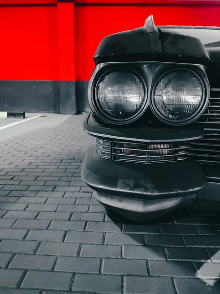 Cadillac Eldorado. Park yerinde duran eski bir araba. Numarası ve sahibi olmayan kirli bir araba. Kırmızı renkli siyah beyaz fotoğraf. Eski bir arabanın farları..