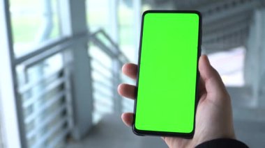 Yeşil ekran akıllı telefon. Bir adamın eli telefonu tutar. Telefonun yeşil ekranına kaydırıyorum. Akıllı telefon görüntüleri. Gri metal arkaplan.